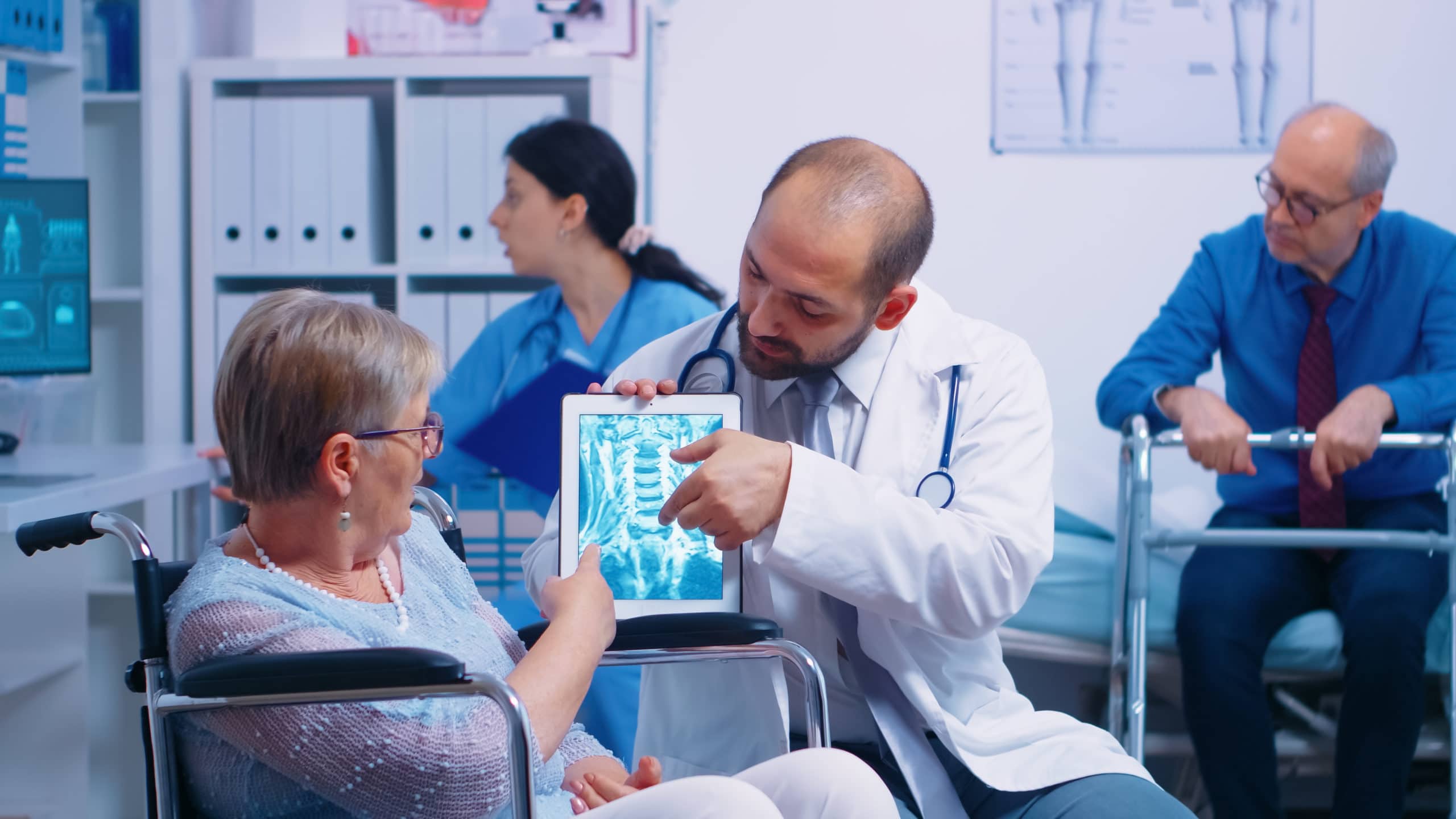 Doctor showing brain X ray image to elderly senior woman in a wheelchair, in a recovery clinic or hospital. Modern health care treatment, rehabilitation program for invalids and handicapped persons